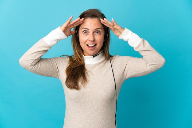 Mujer joven telemarketer sobre pared azul aislada con expresión de sorpresa