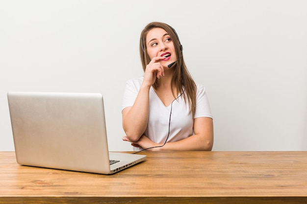 Mujer joven telemarketing relajada pensando en algo mirando un espacio de copia.