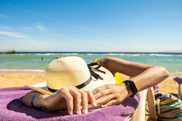 Foto mujer joven tendido en la orilla del sol para tomar el sol