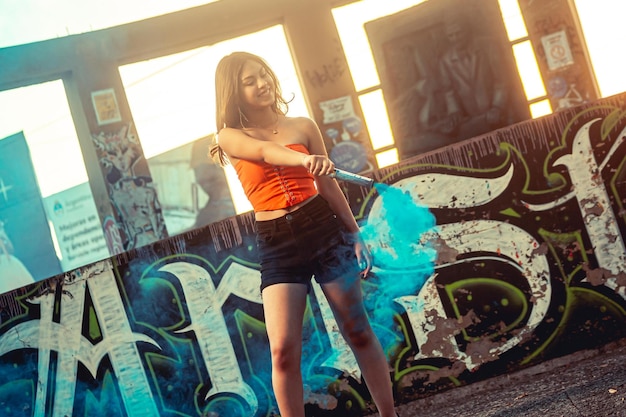 Foto mujer joven, tenencia, coloreado, bengalas, delante de, un, grafiti, pared