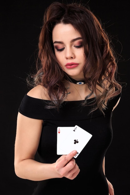 Mujer joven, tenencia, juego de cartas, contra, un, fondo negro