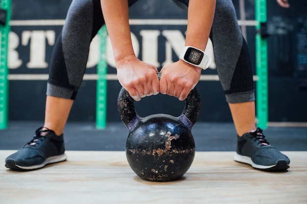 Mujer joven, tenencia, kettlebell, gimnasio interior, entrenamiento