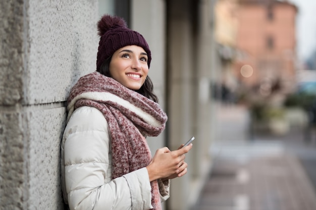 Foto mujer joven, tenencia, smartphone, y, mirar hacia arriba