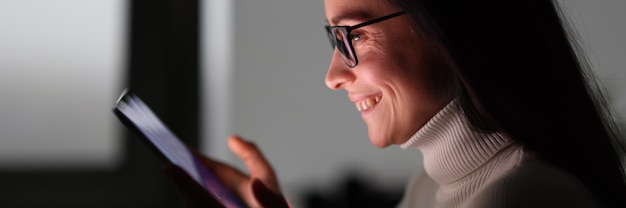 Foto mujer joven, tenencia, teléfono móvil, por la noche