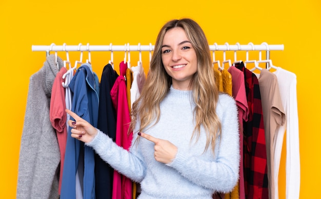 Mujer joven en una tienda de ropa apuntando con el dedo al lado