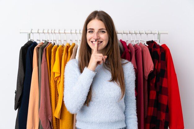 Mujer joven en una tienda de ropa haciendo gesto de silencio