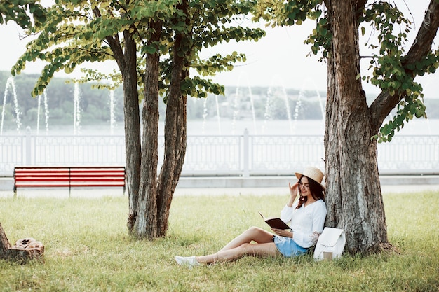 Mujer joven tiene fin de semana y se sienta en el parque durante el día