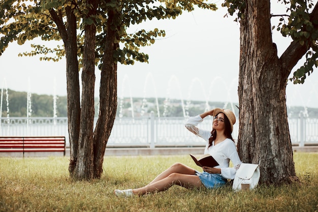 Foto mujer joven tiene fin de semana y se sienta en el parque durante el día