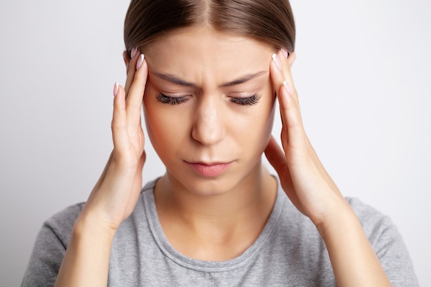 Una mujer joven tiene un fuerte dolor de cabeza.