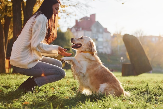 Mujer joven tiene un paseo con Golden Retriever en el parque