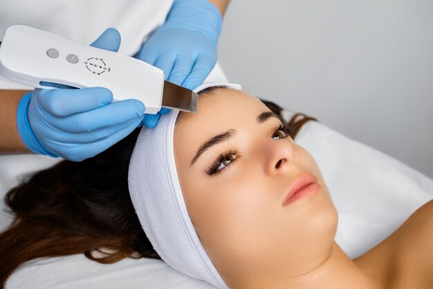 Una mujer joven tiene un procedimiento de peeling de piel por ultrasonido en un salón de belleza