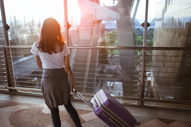 Mujer joven tirando de la maleta en la terminal del aeropuerto. copia espacio