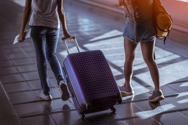 Mujer joven tirando de la maleta en la terminal del aeropuerto moderno Chico que viaja con su equipaje mientras espera el transporte Vista trasera Espacio de copia