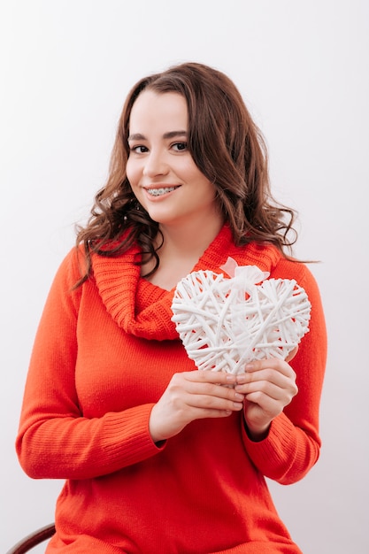 Mujer joven con tirantes sosteniendo un corazón