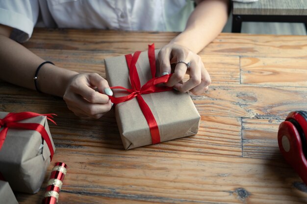 Mujer joven de tiro recortada envolver regalos para Navidad.