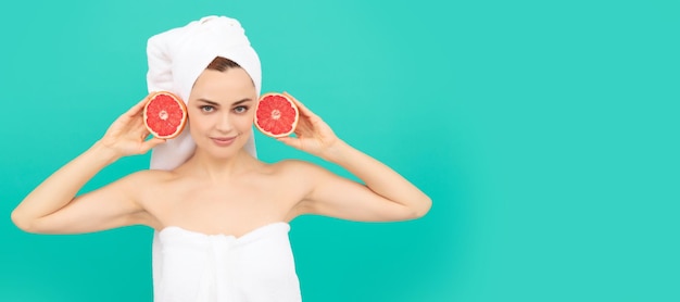 Mujer joven en toalla después de la ducha con pomelo sobre fondo azul vitamina c Hermosa mujer