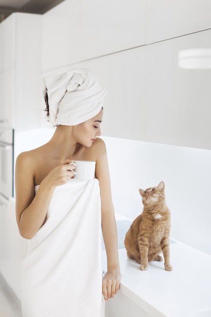 Mujer joven en toalla disfrutando de un café en casa