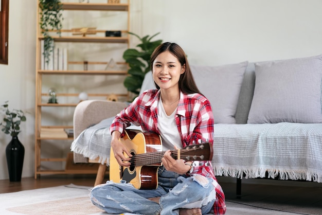 Foto la mujer joven toca la guitarra y practica para cantar la canción a