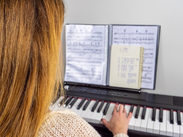 Foto mujer joven tocando el piano con una partitura borrosa en el fondo