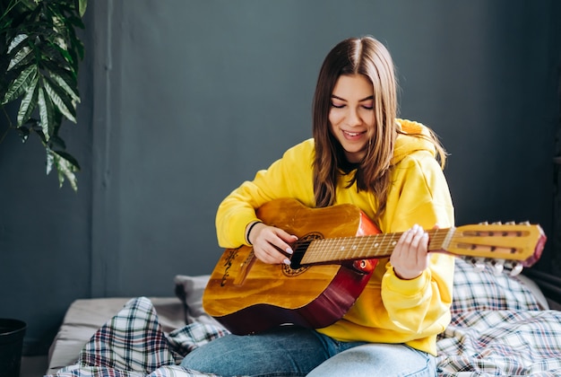 Mujer joven tocar guitarra acústica en casa