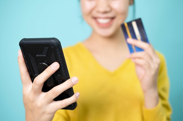 Mujer joven se toma una foto usando un teléfono inteligente y una tarjeta de crédito para pagar en línea