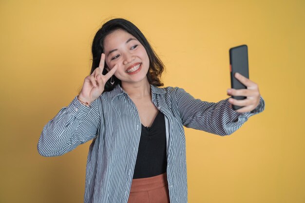 Mujer joven toma un selfie con gesto de dedo de signo v