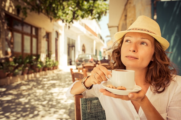 Mujer joven tomando café en la cafetería de verano