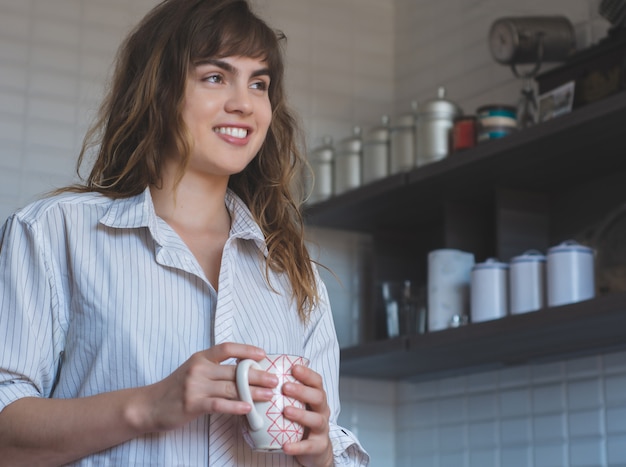 Mujer joven tomando café en casa