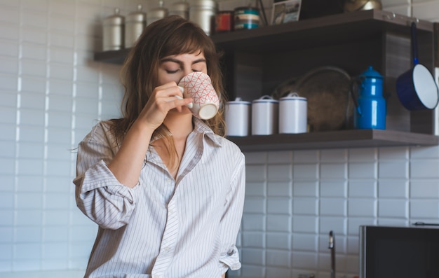 Mujer joven tomando café en casa