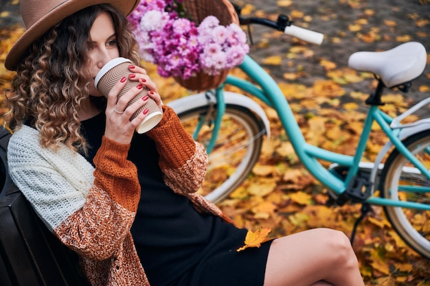 Mujer joven tomando café en el parque otoño