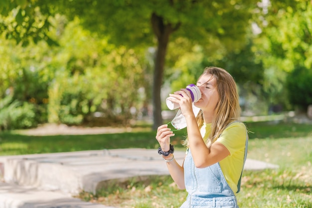 Mujer joven tomando café y en el parque durante la pandemia