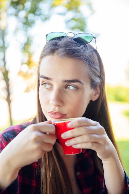 Mujer joven tomando café en el parque