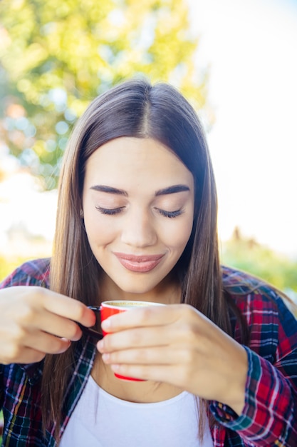 Mujer joven tomando café en el parque