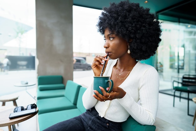 Mujer joven tomando un descanso y bebiendo café en la cafetería