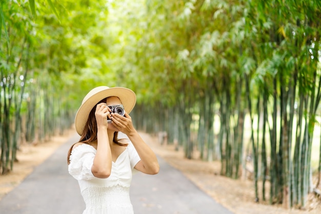 Mujer joven tomando fotos en un bosque de bambú