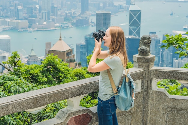 Mujer joven tomando fotos del puerto de victoria en Hong Kong, China.