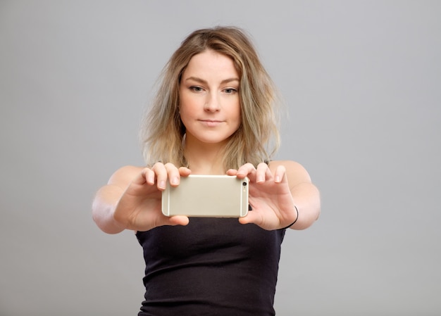 Mujer joven tomando fotos a través de su teléfono