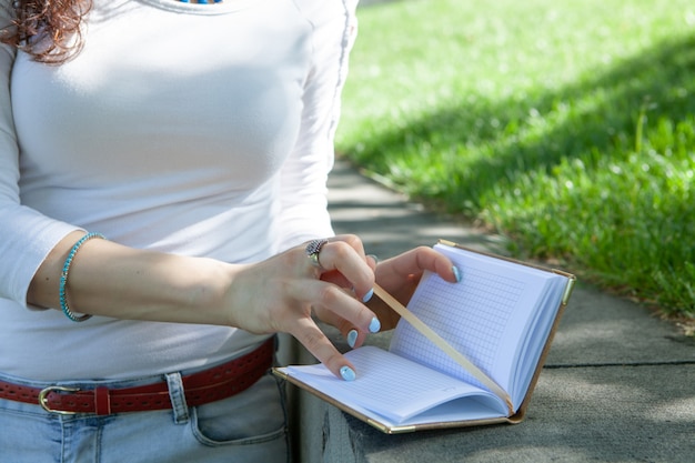 Mujer joven tomando notas en un cuaderno en el parque