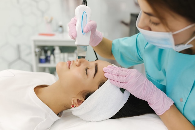 Mujer joven tomando procedimiento de belleza en el salón de spa