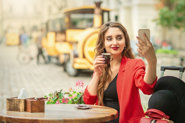 Mujer joven tomando selfie en café al aire libre