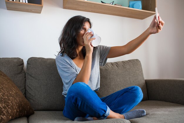 Foto mujer joven tomando una selfie en casa