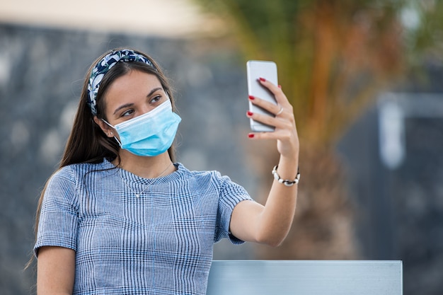 Mujer joven tomando un selfie con mascarilla