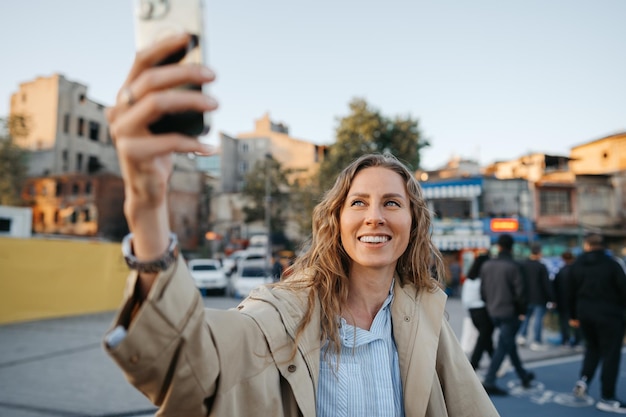 Mujer joven tomando selfie en smartphone en la calle