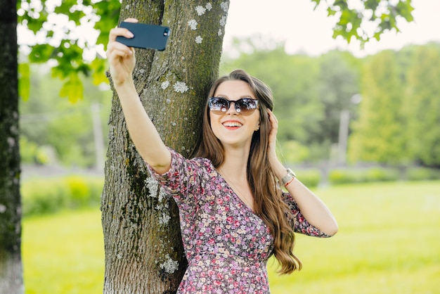 Mujer joven tomando selfie con teléfono en el parque