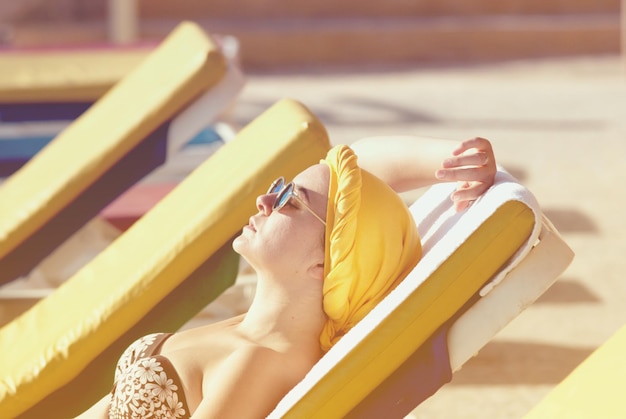 mujer joven tomando el sol en el mar y aplicando protector solar