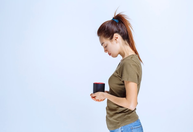 Mujer joven tomando una taza de bebida por la mañana