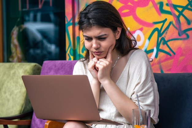 Una mujer joven trabaja en una computadora en una terraza de colores brillantes de un café