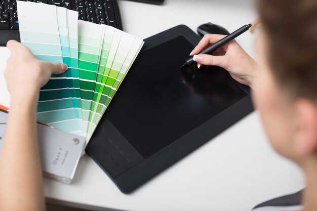 Mujer joven trabaja con panel de color y tableta digital
