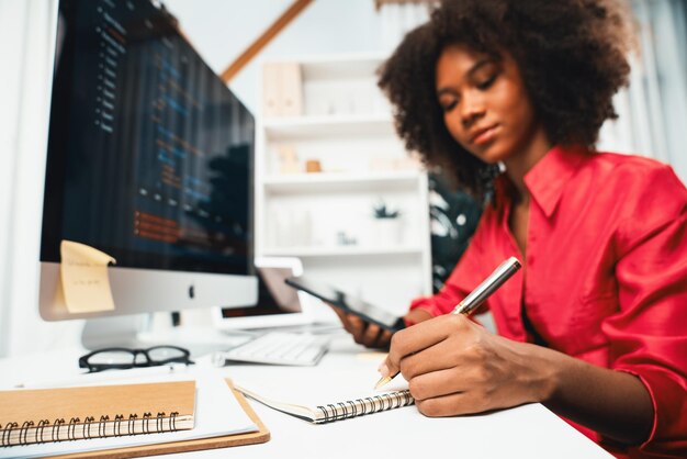 Mujer joven trabajadora africana creando codificación desarrollador de sitios web pensando diseñador de información de datos en la oficina de casa centrándose en la computadora portátil Concepto de centro de datos analíticos en java trabajo de proyecto Tastemaker