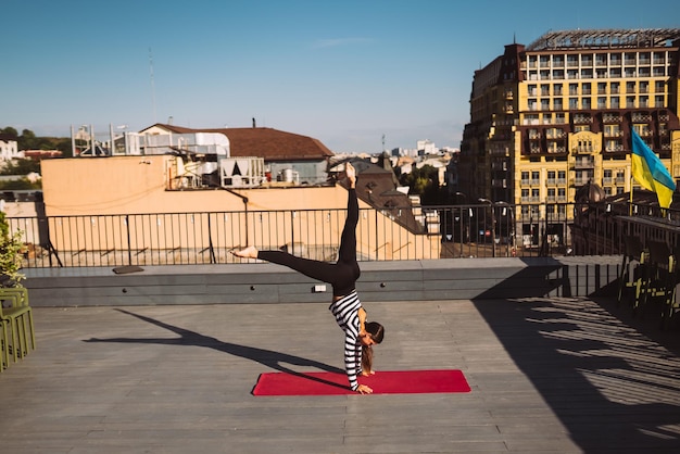 Mujer joven trabajando al aire libre y haciendo ejercicio de parada de manos de yoga